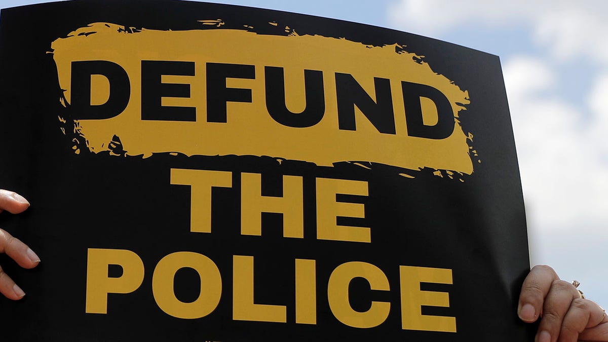 A person holds up a sign advocating for defunding the police as people gather to mark Juneteenth, Friday, June 19, 2020, in St. Louis. Juneteenth is the holiday celebrating the day in 1865 that enslaved black people in Galveston, Texas, learned they had been freed, more than two years after the Emancipation Proclamation was signed. (AP Photo/Jeff Roberson)