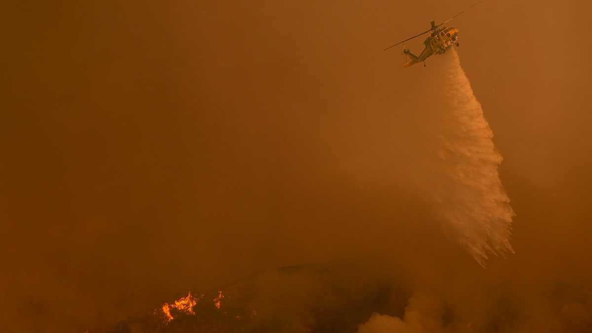 Water is dropped on the Palisades Fire by helicopter in Mandeville Canyon