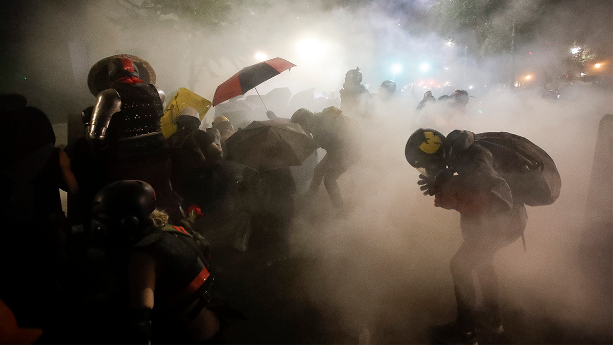 Federal officers launch tear gas at a group of demonstrators