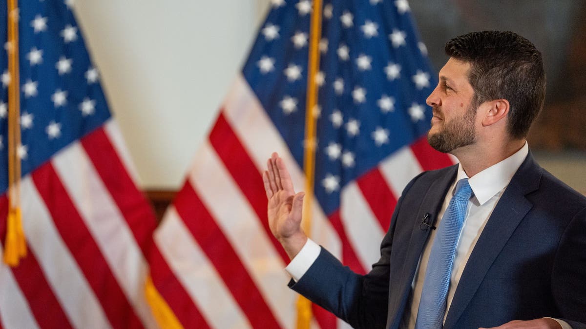 Florida AG James Uthmeier raises a hand as he is sworn into office in front of a US flag