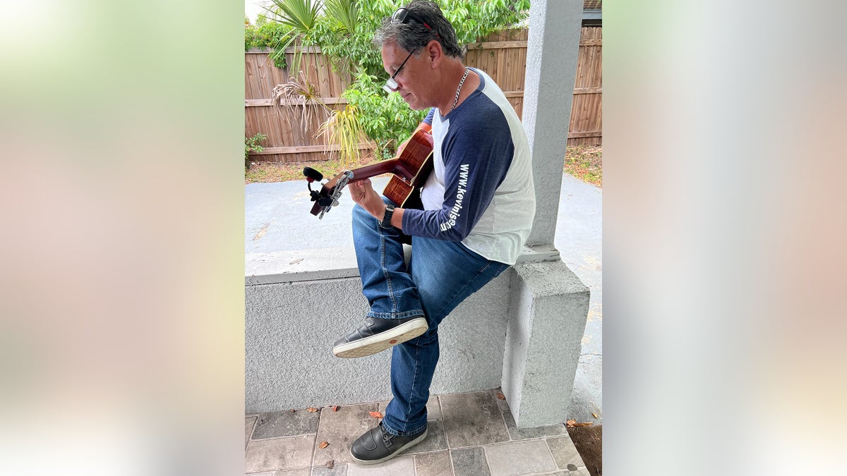 Leo Schofield playing the guitar in casual wear.
