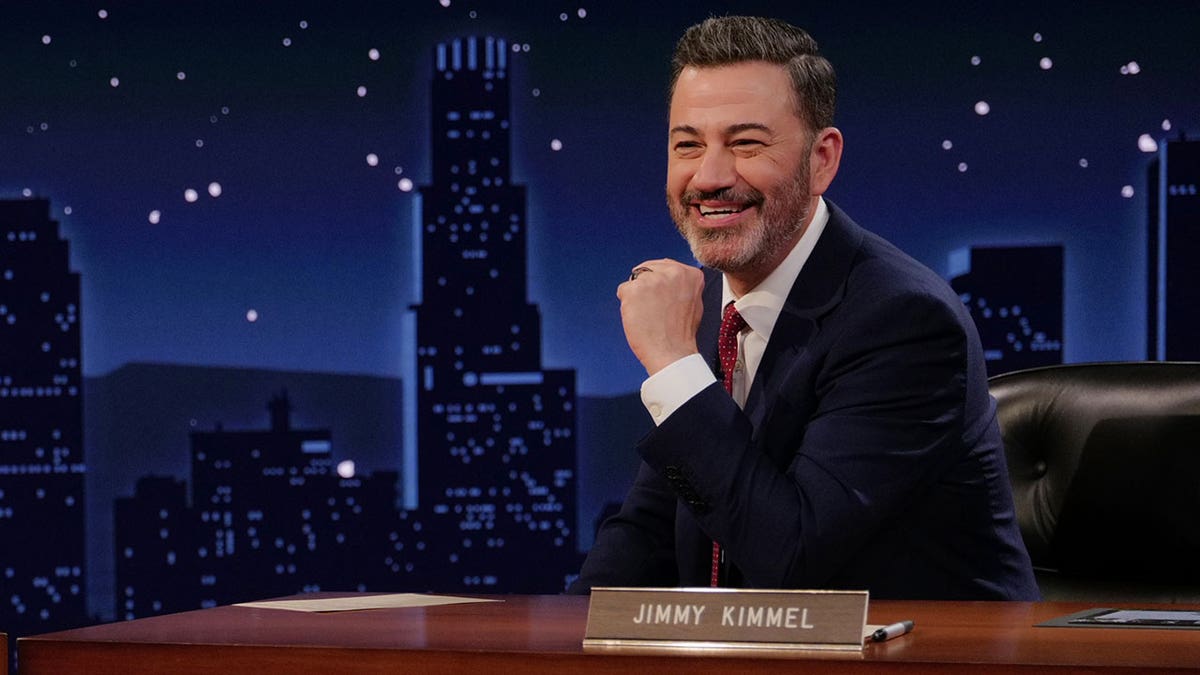 Jimmy Kimmel sitting at a desk on set