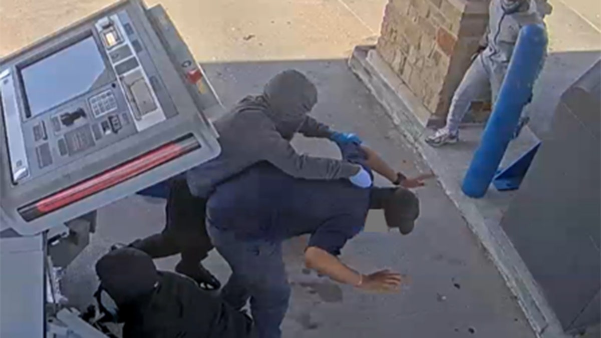 An ATM worker is held to the ground during a robbery