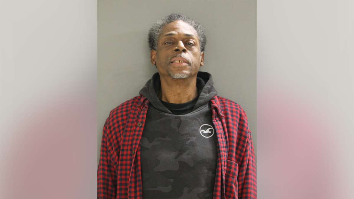 Vance Patton wearing a flannel shirt and sweatshirt in a booking photo.