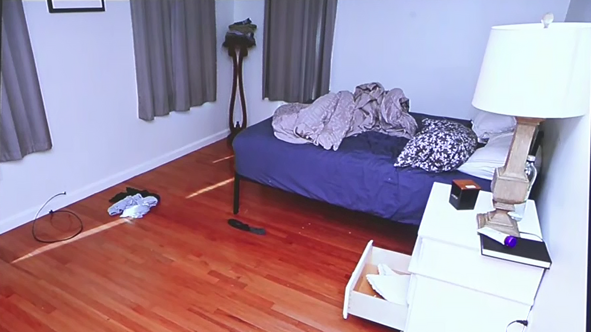 A small bedroom with a simple bed, night table and lamp