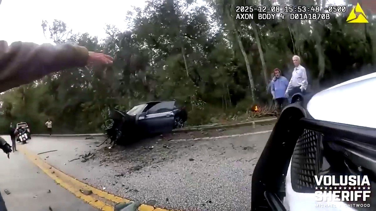 wrecked BMW on side of road as Calvin Curtis Johnson stands nearby