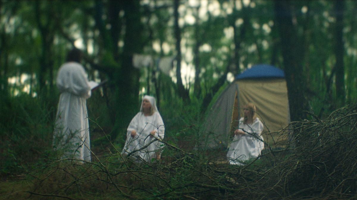 A scene of Elizabeth Smart in white robes standing between her captors.