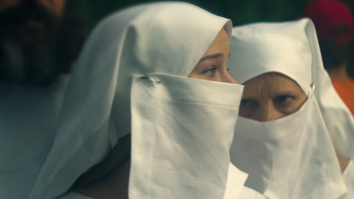 A scene showing an actress playing Elizabeth Smart covered in white garments from head to toe.