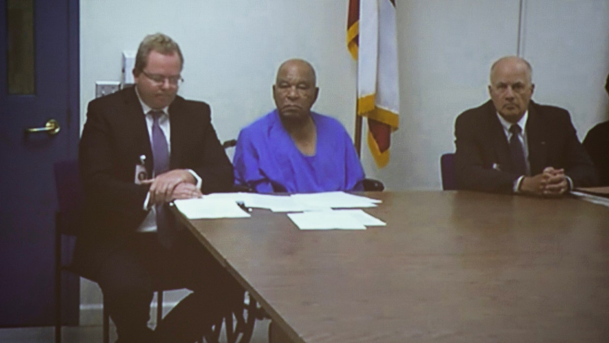 Samuel Little sitting in between attorneys listening at a court case.
