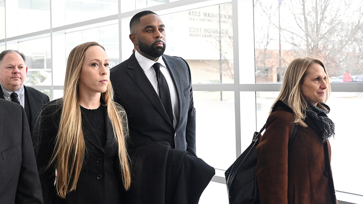 Sherrone Moore, wife, and attorney walk into court