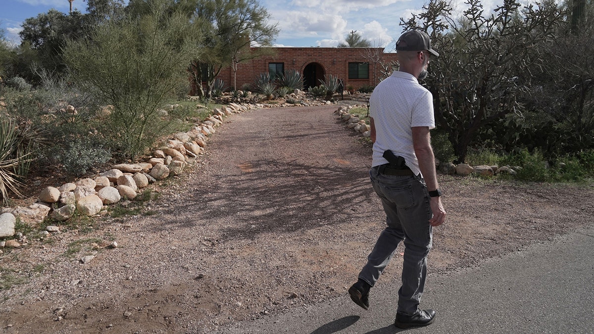 Investigator searching the grounds of Nancy Guthrie's property in the Catalina Foothills.