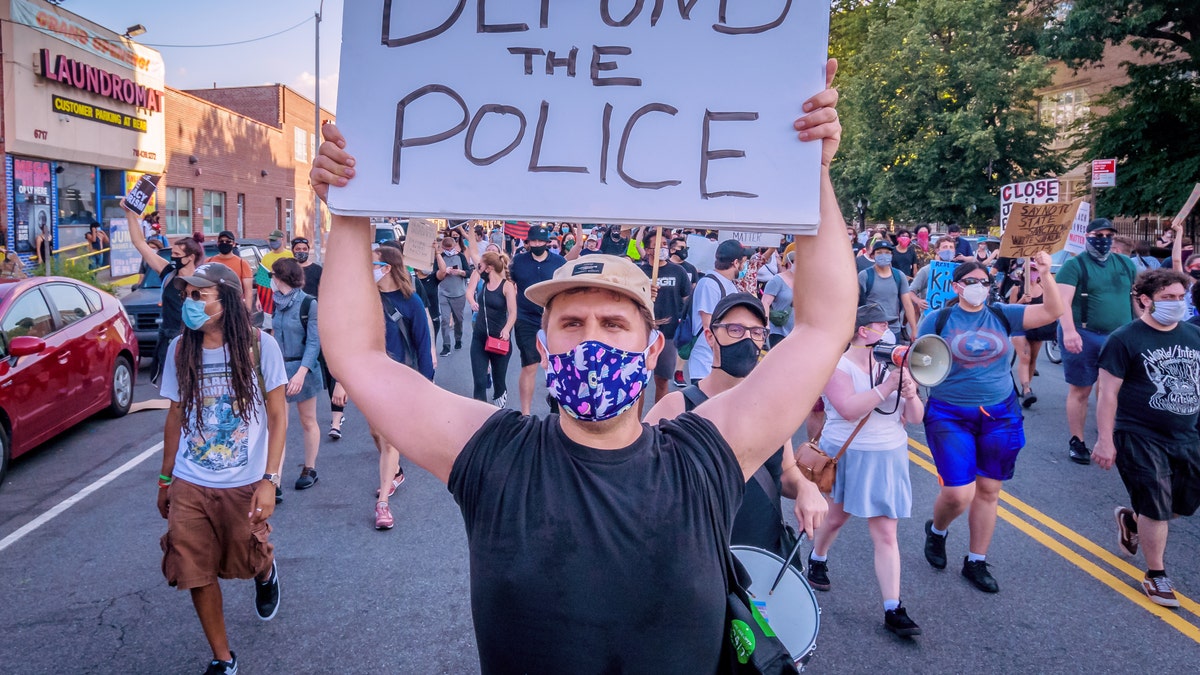 A demonstrator in New York holds a "defund the police" sign