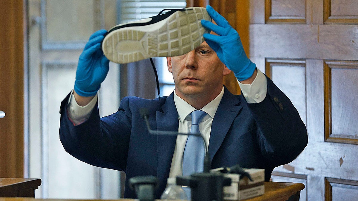 A man holding up a sneaker in court wearing a suit.