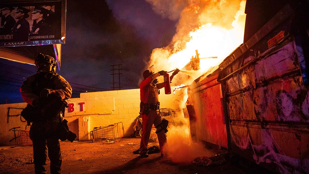 cop putting out fire in LA