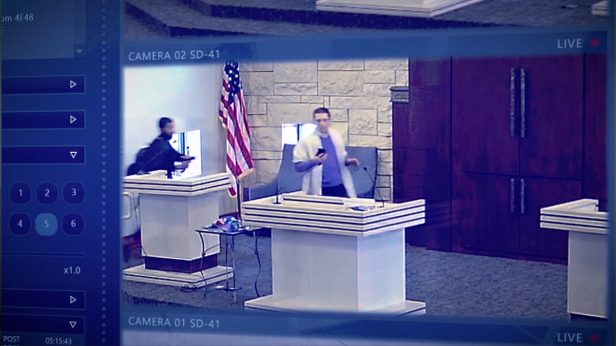 An armed Malik Faisal Akram watching one of his hostages, Rabbi Cytron-Walker.