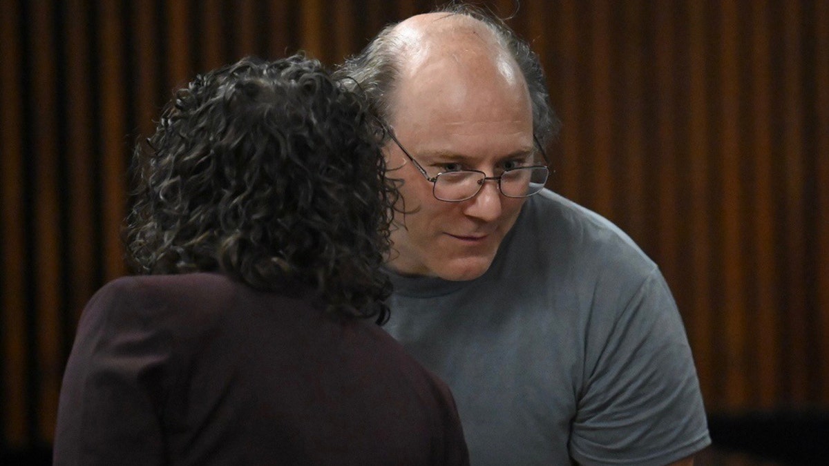 Lorenz F. Kraus leans forward to listen to his attorney