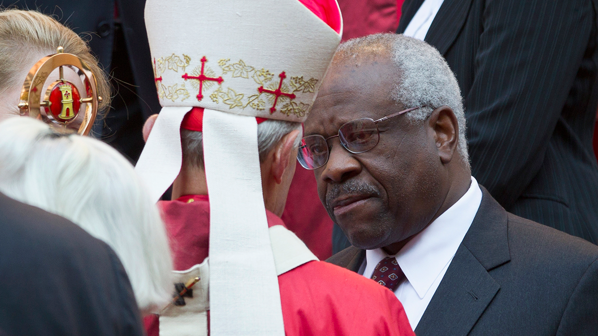 Cardinal Donald Wuerl, in his priestly robes, speaking with US Supreme Court Justice Clarance Thomas, who is wearing a dark suit