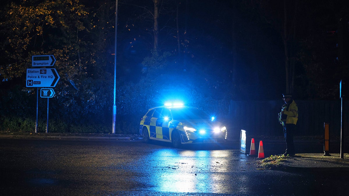 Police officer standing by police car at scene of stabbing