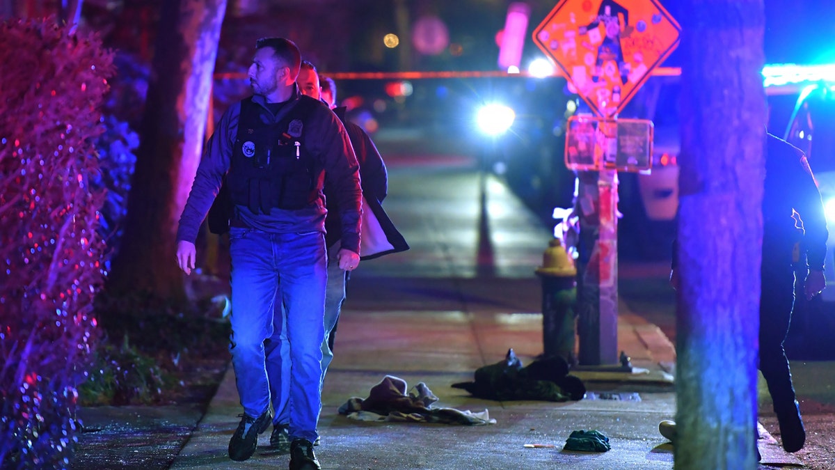 A law enforcement official walks past articles of clothing on a sidewalk near an entrance to Brown University, Saturday, in Providence, R.I., during the investigation of a shooting.