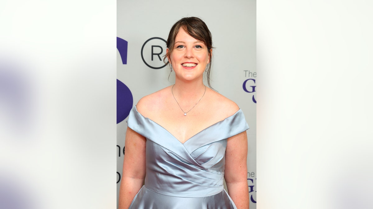 Patricia E. Gillespie wearing a satin off the shoulder dress and smiling at a film premiere.