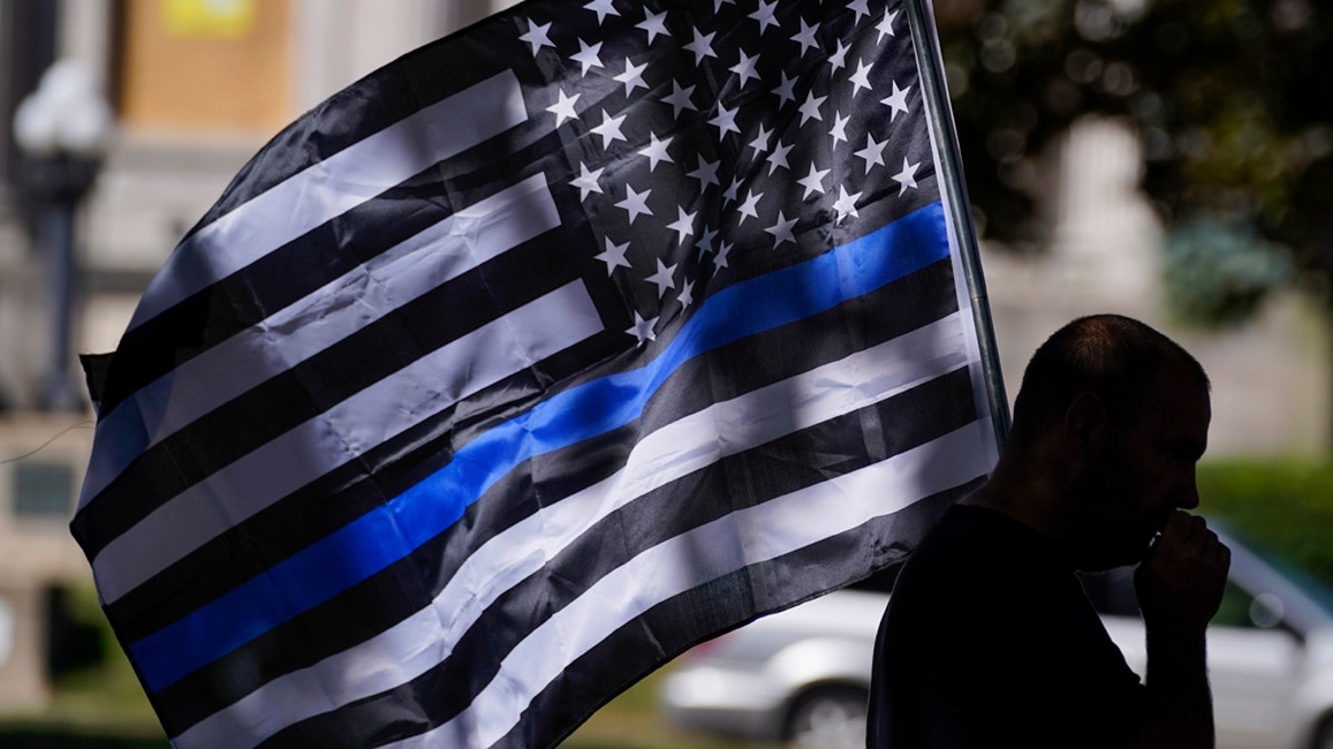 person carrying Thin Blue Line flag