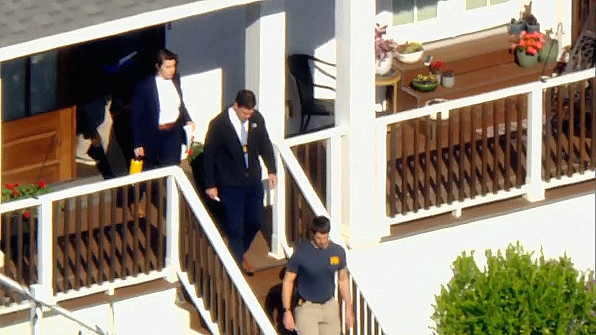 officials walk out of door of home