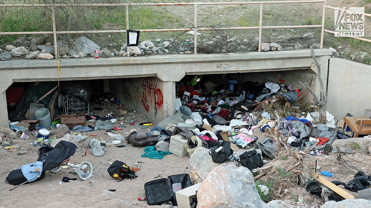A culvert near Nancy Guthrie's home is filled with various discarded items and debris in an outdoor area.