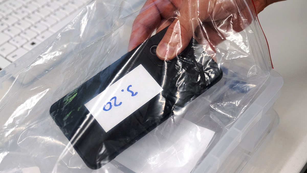 A smartphone is placed in a plastic evidence bag.